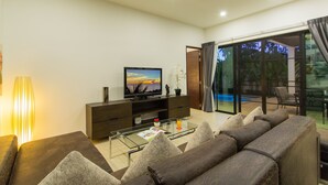 En moderne stue med et fladskærms-tv, et sofabord i glas og en sofa.