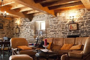 Una habitación acogedora con paredes de piedra, un sofá de cuero y techo de madera.
