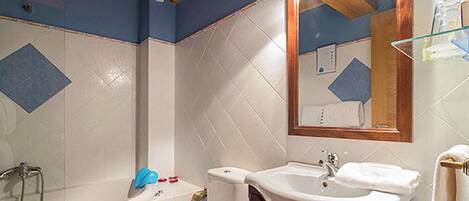 A bathroom with a bathtub, a sink, and a mirror.