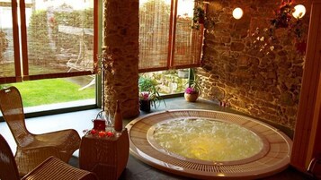 Un jacuzzi en una habitación con paredes de piedra y ventanas grandes.