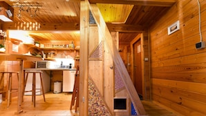 Un intérieur en bois comprenant un espace cuisine, un escalier en bois et un petit coin réservé aux animaux de compagnie.