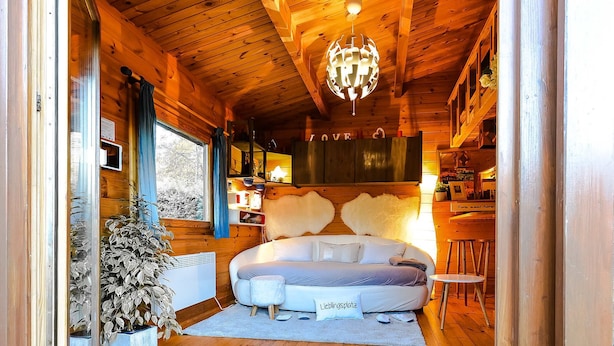 Une chambre confortable dans un chalet en rondins, avec un grand lit, un lustre et des murs en bois.