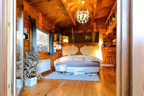 Een gezellige blokhutkamer met een groot bed, een kroonluchter en houten wanden.
