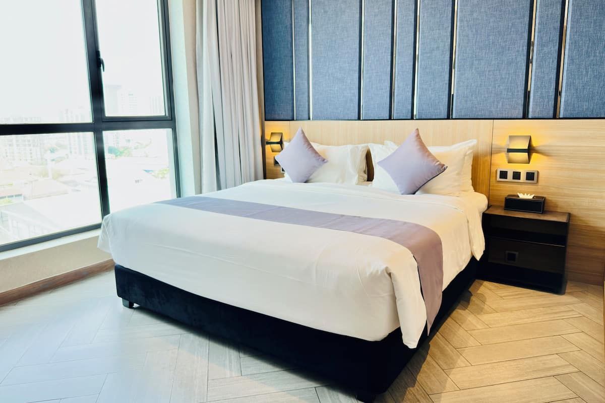 Une chambre d’hôtel moderne avec un grand lit, des tables de chevet et une vue par la fenêtre.