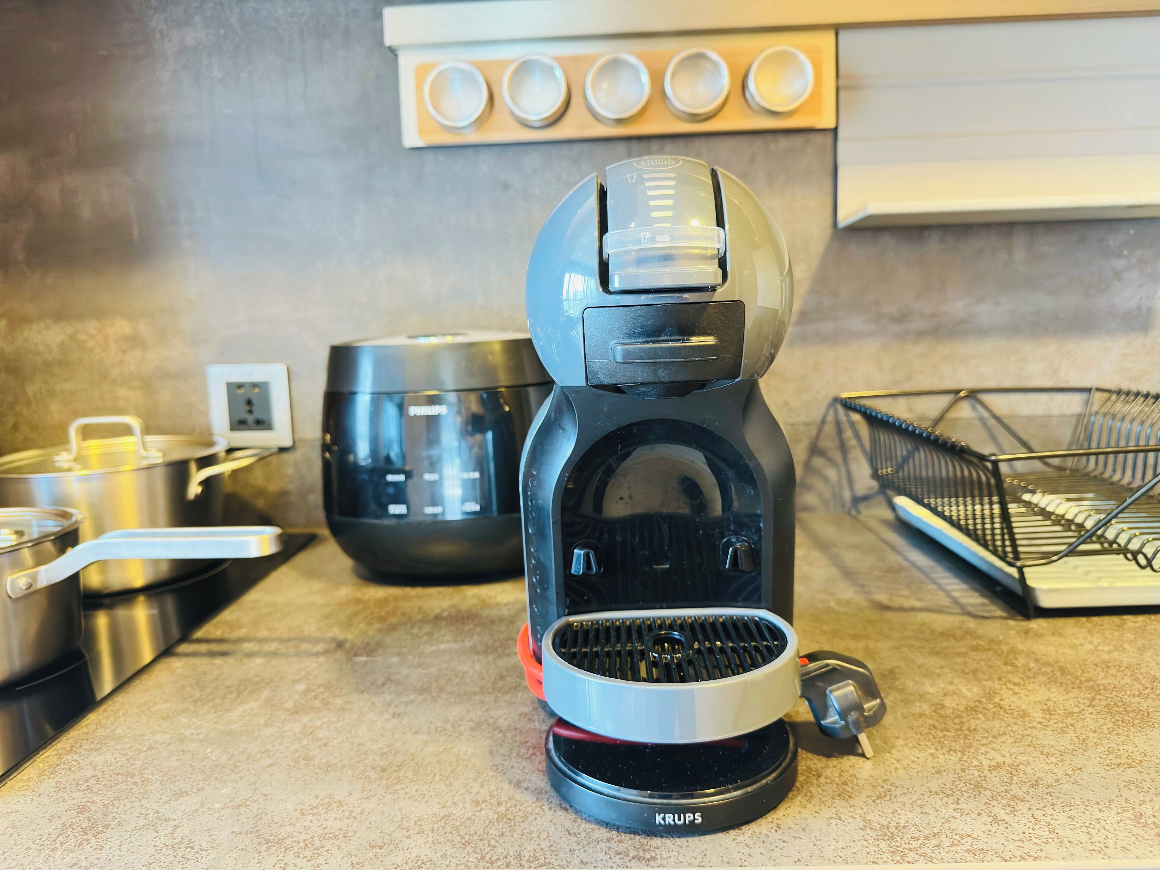 A coffee maker on a kitchen counter with a pot, a bowl, and a basket.