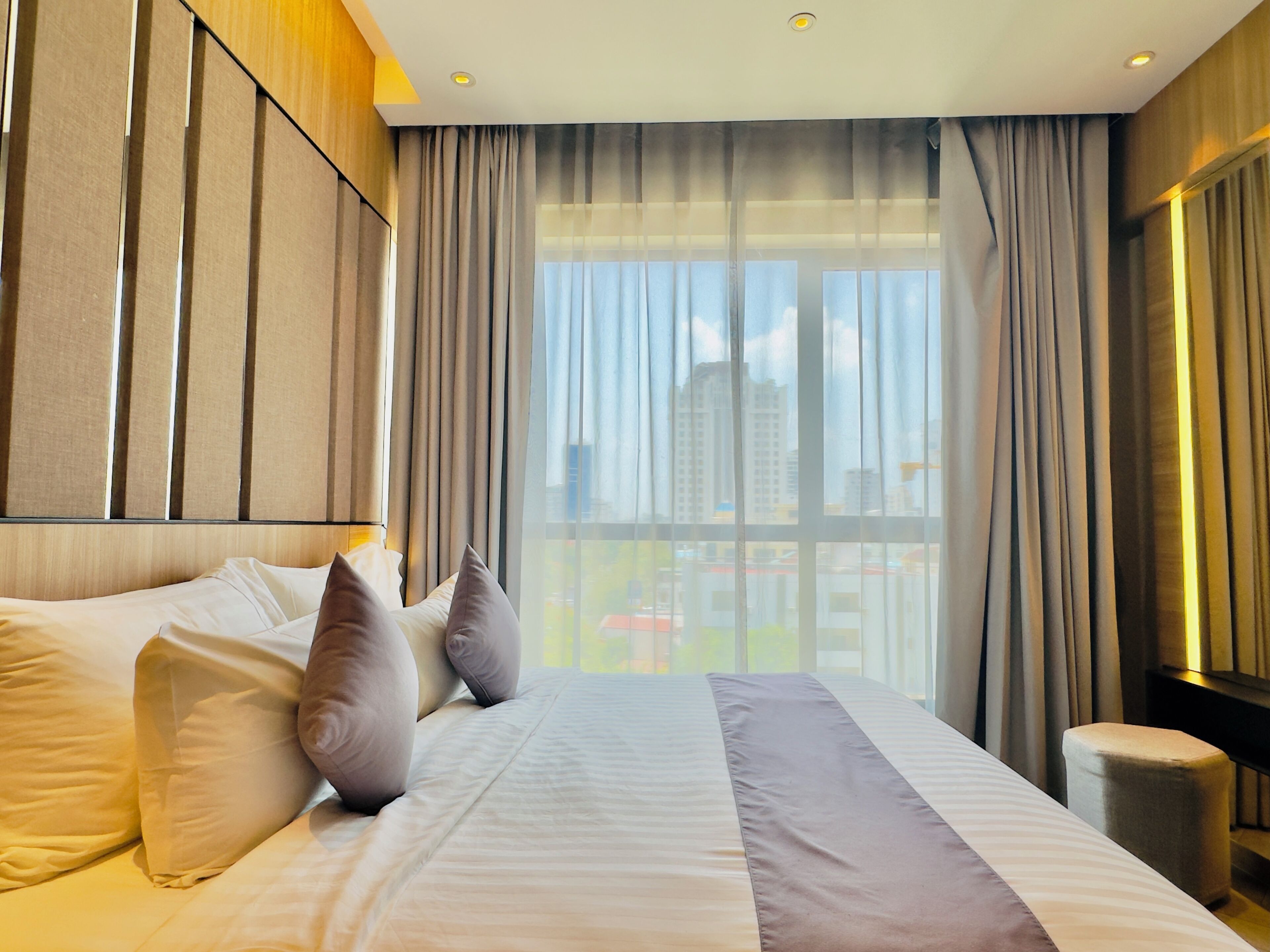 A hotel room with a large bed, a view of the city through the window, and a modern design.