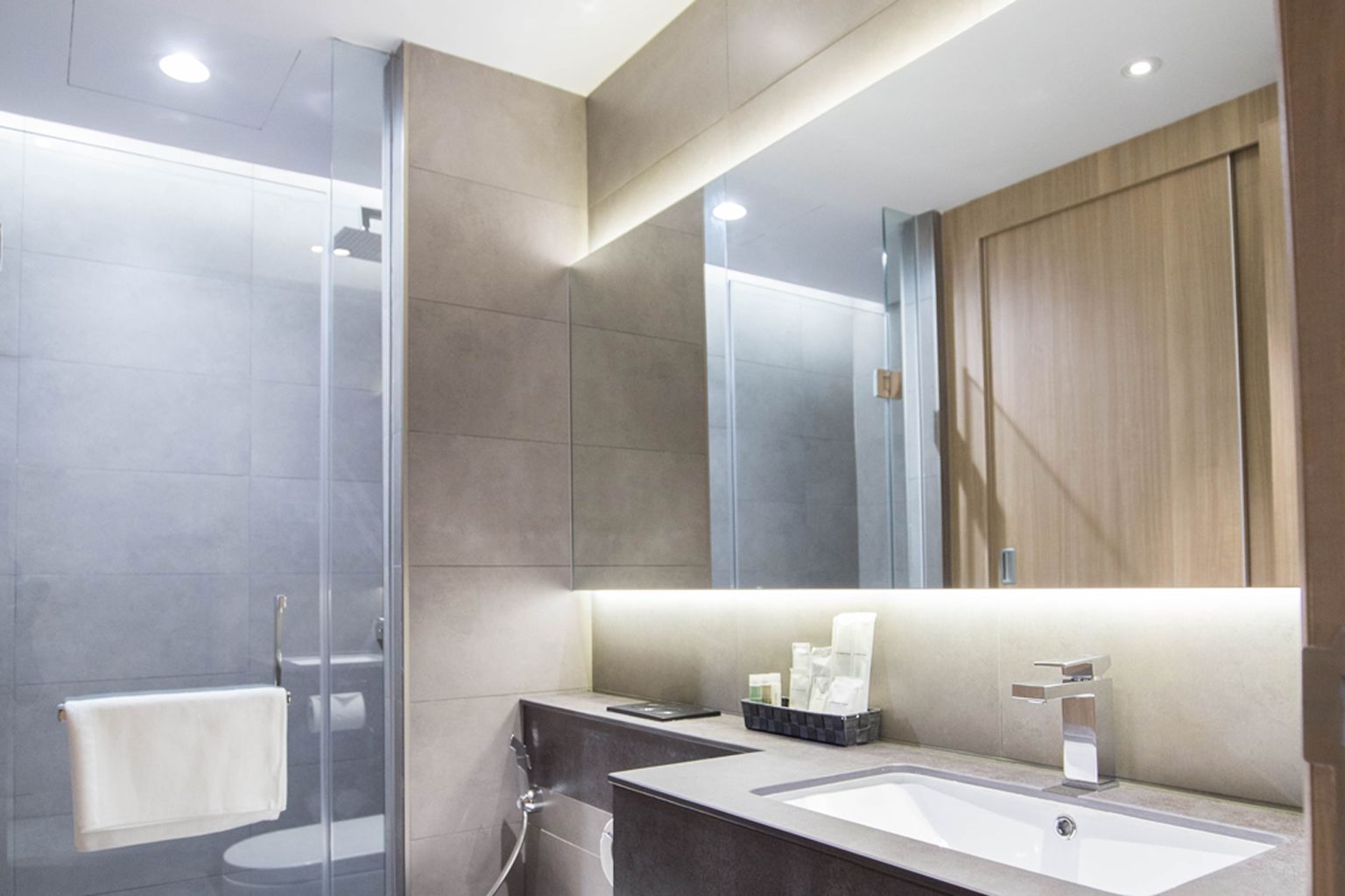 Une salle de bain moderne avec une douche à parois de verre, un grand miroir et un meuble-lavabo.
