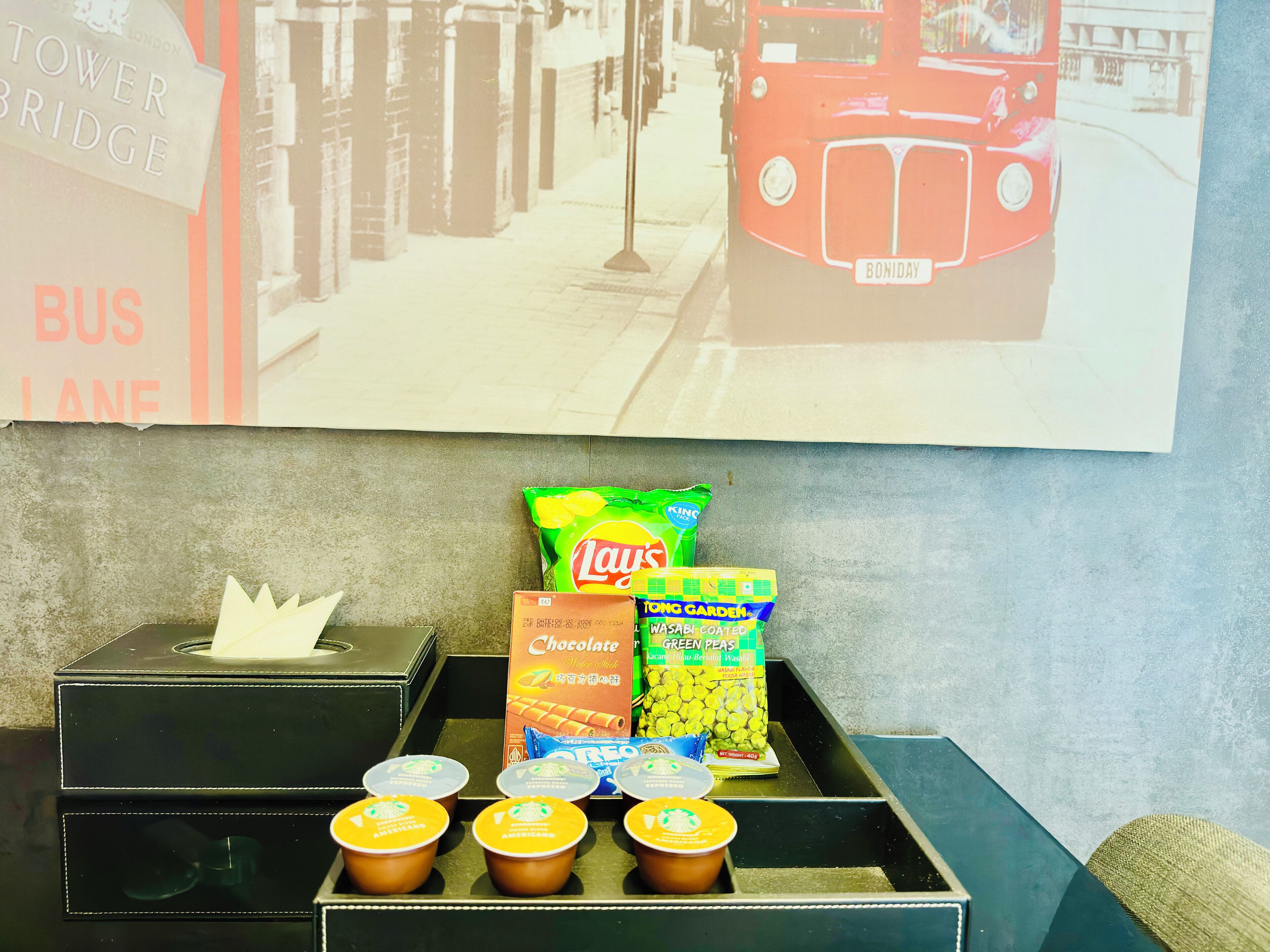 A tray with snacks and drinks, a tissue box, and a poster of a bus on a wall.