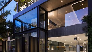 Un edificio moderno con facciata in vetro, un cartello con la scritta 'RESIDENCE' e una zona d'ingresso ben illuminata.
