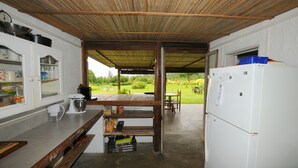Een keuken met een houten plafond, een witte koelkast en uitzicht op een tuin.