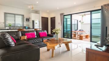 A modern living room with a leather sofa, wooden coffee table, and a flat-screen TV.