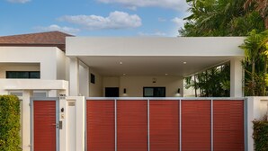 A modern house with a red garage door, a covered driveway, and a white exterior.