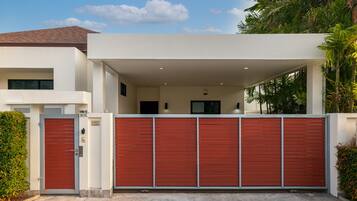 Une maison moderne avec une porte de garage rouge, une allée couverte et une façade blanche.