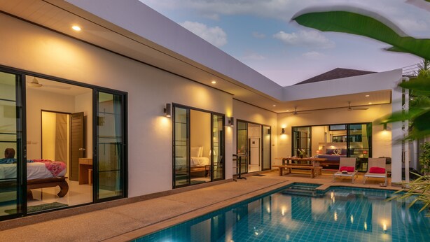 A modern hotel with a swimming pool, large glass doors, and a cozy seating area.