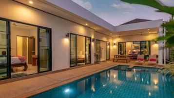 A modern hotel with a swimming pool, large glass doors, and a cozy seating area.