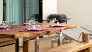 A wooden dining table set with pink placemats and white plates, glasses, and cutlery.