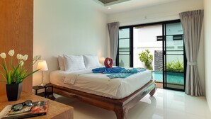 A modern hotel room with a large bed, a bedside table with a lamp, a potted plant, and a view of an outdoor swimming pool.