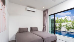 A modern bedroom with a large bed, an air conditioning unit, and a view of a swimming pool. - Large 3BR Villa with Big Pool by Intira (Rawai)