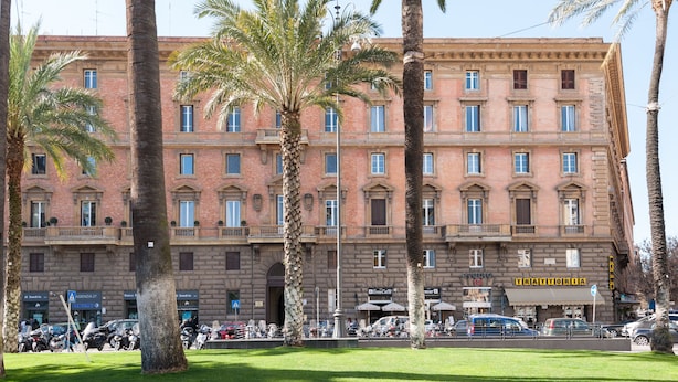 A multi-story building with a classical architectural style, featuring a central courtyard with palm trees. - Mybedcavour (Rome)