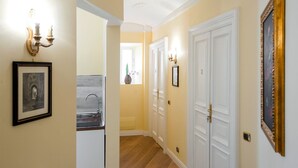 A hallway with a sink, framed artwork, and a door with a gold frame. - Mybedcavour (Rome)