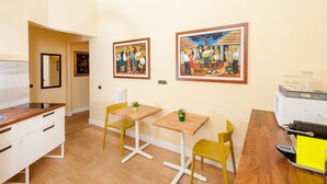 A room with a wooden dining table, two yellow chairs, a white radiator, and two framed paintings on the wall. - Mybedcavour (Rome)