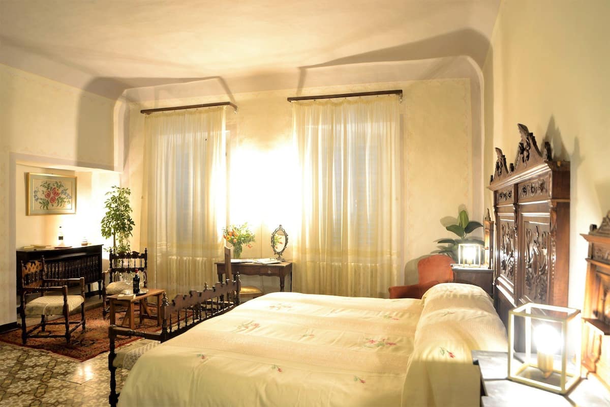 Ein traditionell eingerichtetes Schlafzimmer mit einem großen Bett, einer Holzkommode, einem Schreibtisch mit Stuhl und einem Blumentopf.