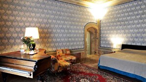 A room with a piano, a bed, a chair, and a rug. - Il Palazzo Boutique B&B (Montalcino)