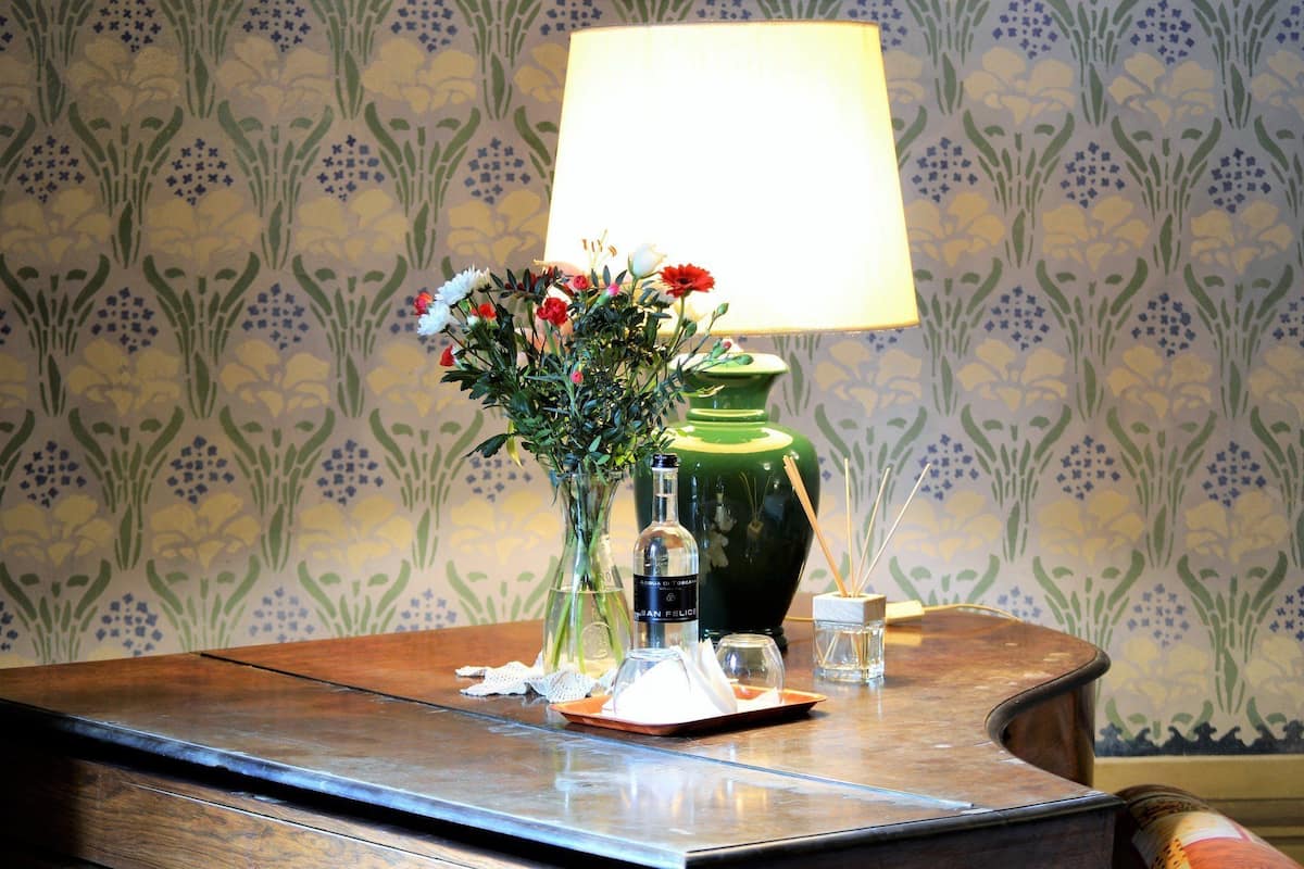 Ein Holztisch mit einer Blumenvase, einer grünen Flasche und einer Glasflasche mit Etikett.