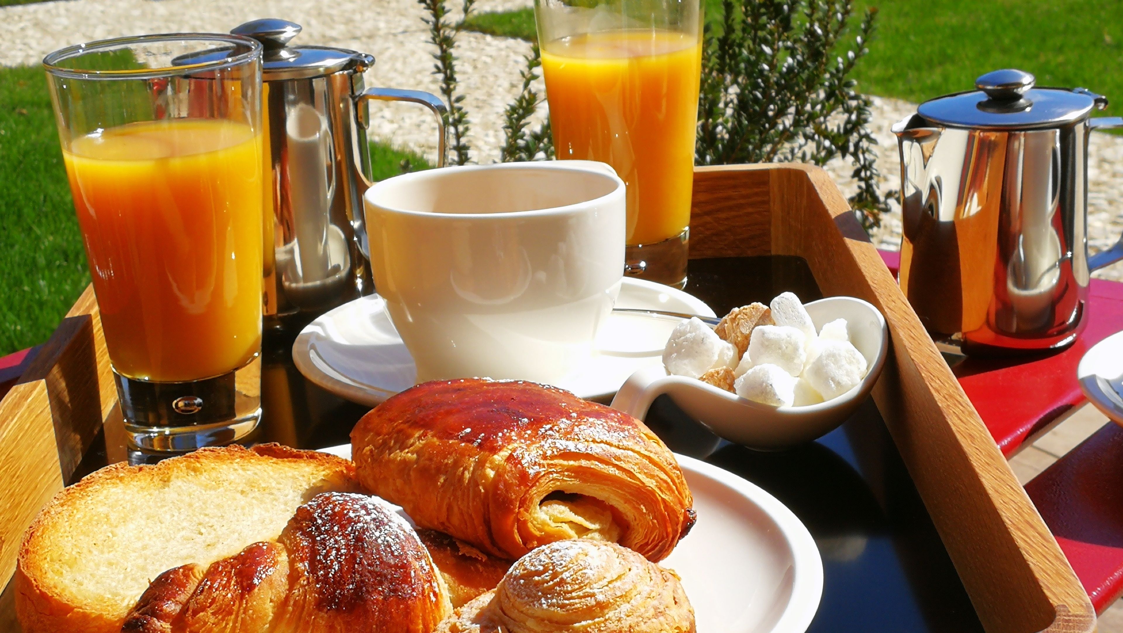 A breakfast tray with croissants, bread, a cup, and glasses of orange juice.