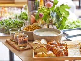 Un bufé con diversos alimentos, como pan, bollería y ensalada.