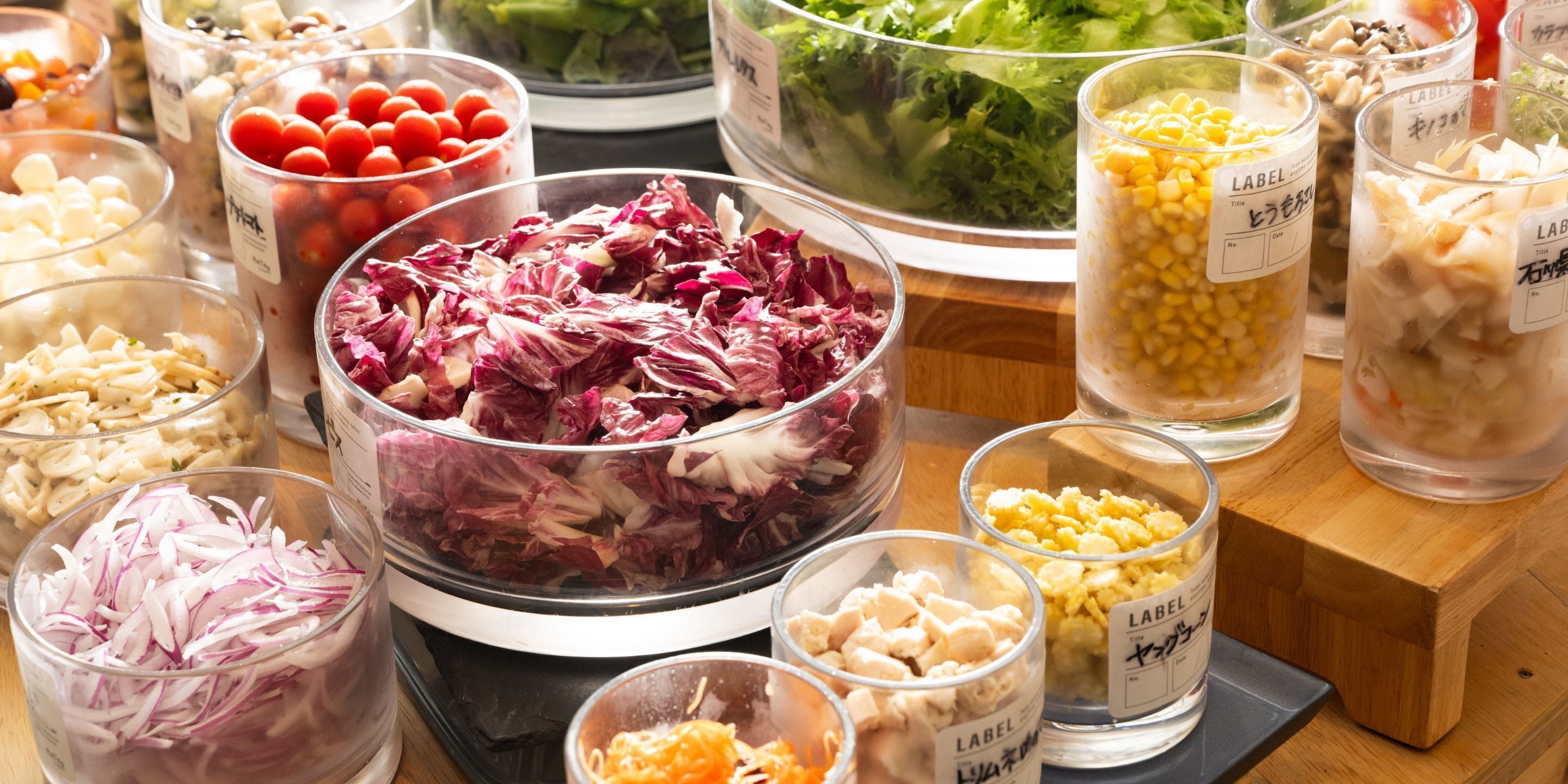 A variety of food items in transparent containers on a wooden table.