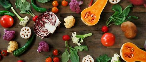 Une variété de légumes frais et d’herbes aromatiques est disposée sur une surface en bois.