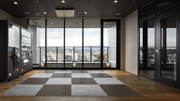 A spacious lobby with a checkered floor, a vending machine, and a view of the city through large glass doors.