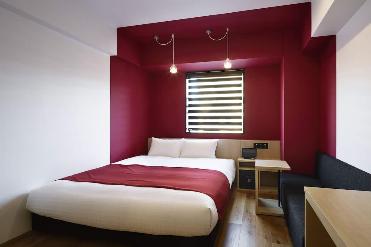 A modern bedroom with a bed, bedside table, and a desk with a chair.