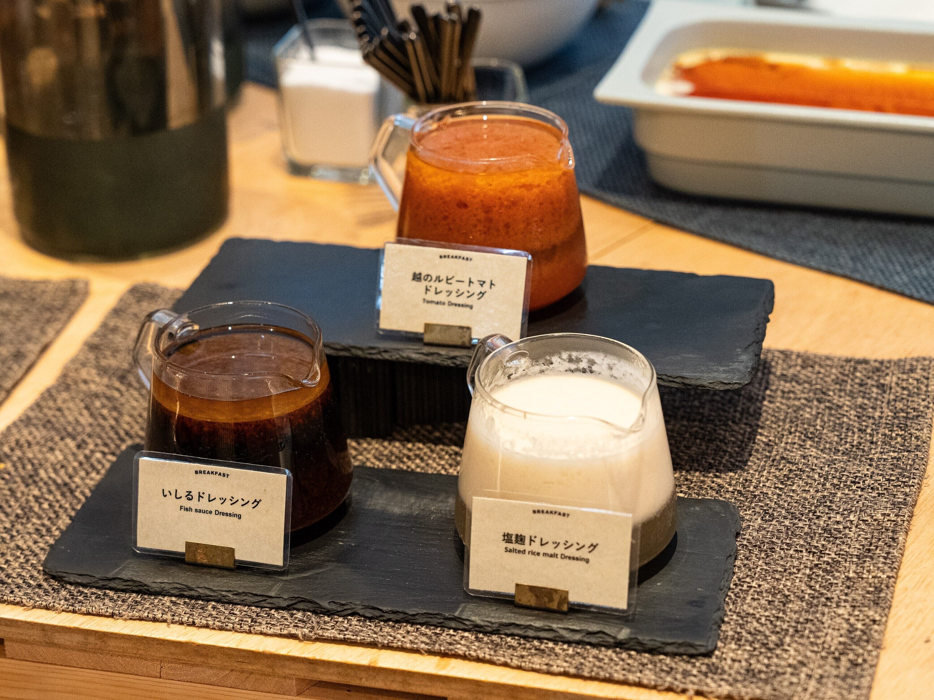 A table with three labeled containers of food: fish sauce dressing, tamate dressing, and salted rice malt dressing.