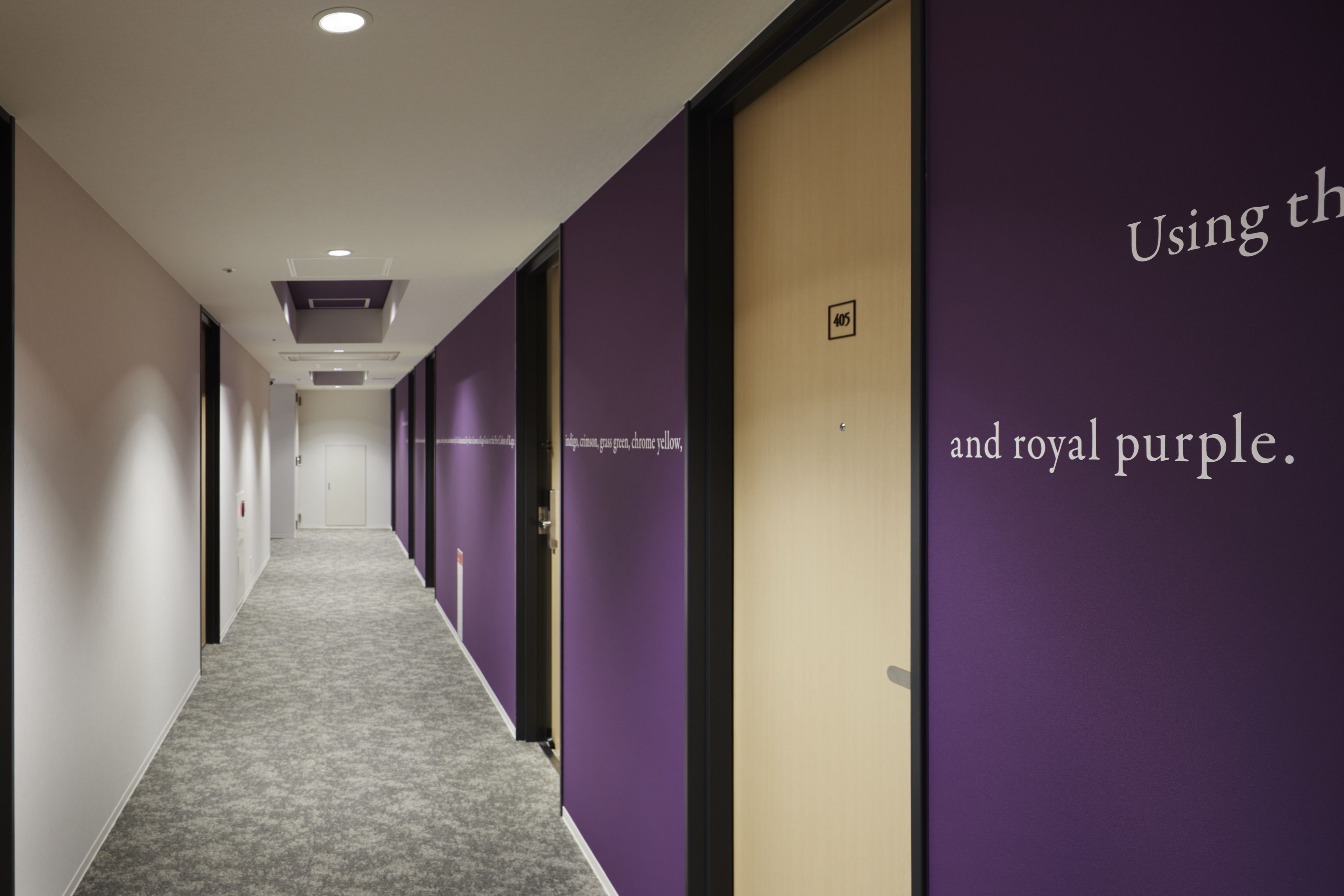 A hallway with purple and beige walls, carpeted floor, and doors numbered 405 and 406.