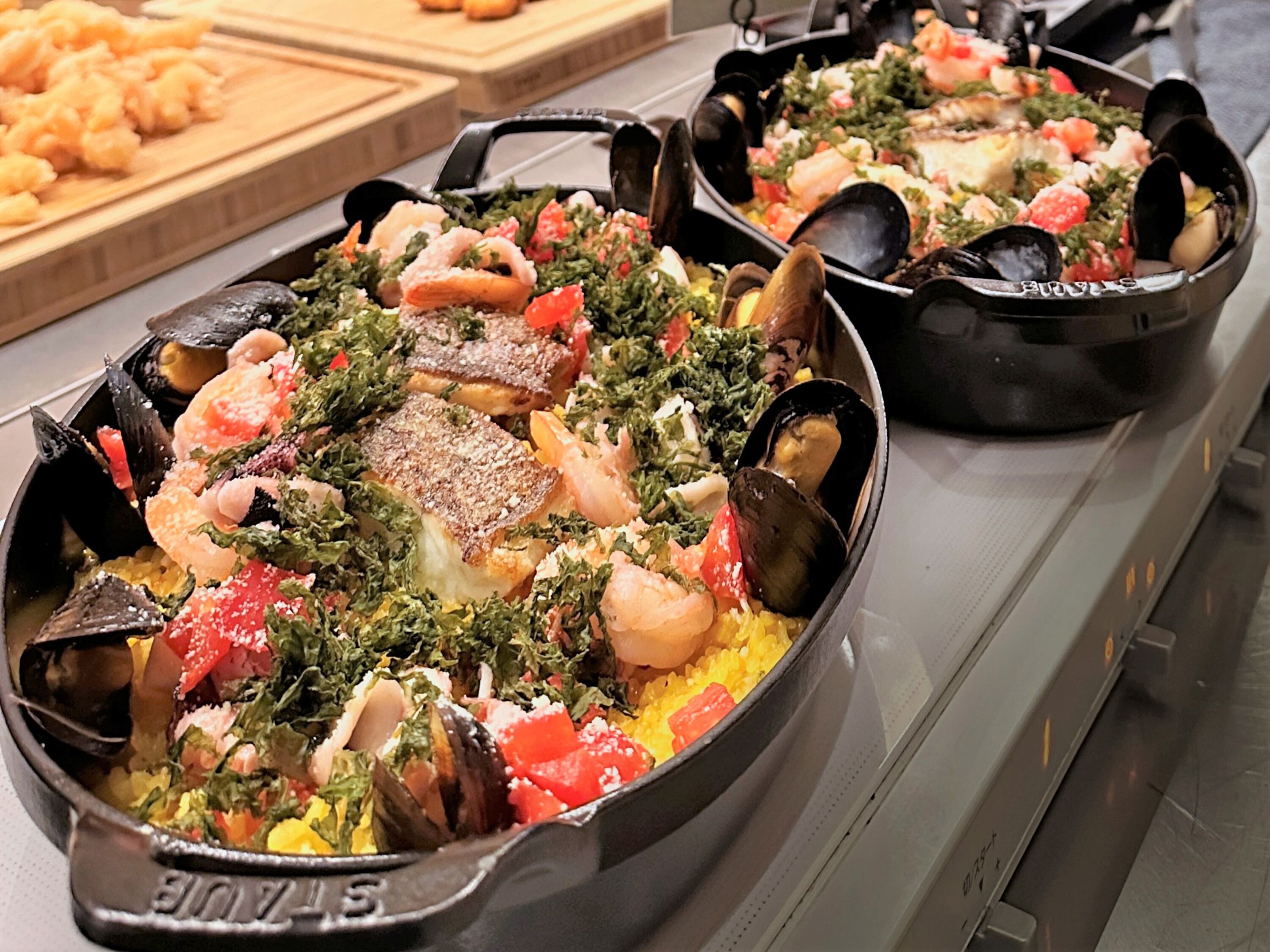 A buffet with seafood dishes, including mussels, shrimp, and fish, served in black pans.