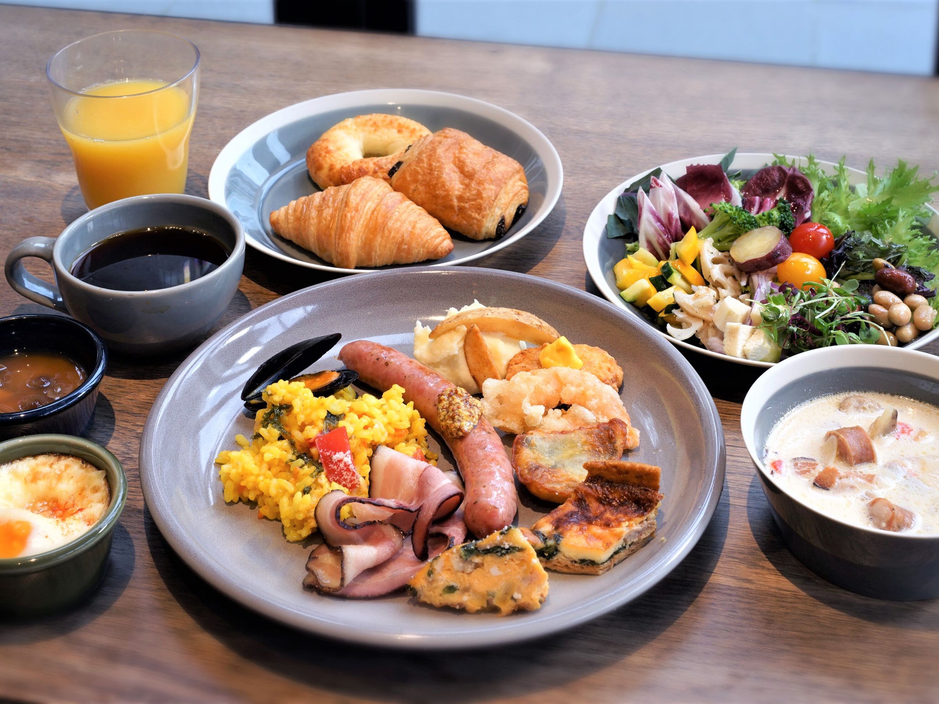 A breakfast table with plates of food, a glass of orange juice, and a cup of coffee.