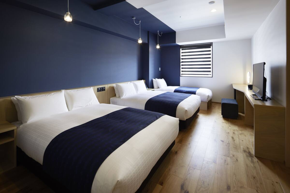 A modern hotel room with two beds, a desk, and a TV.