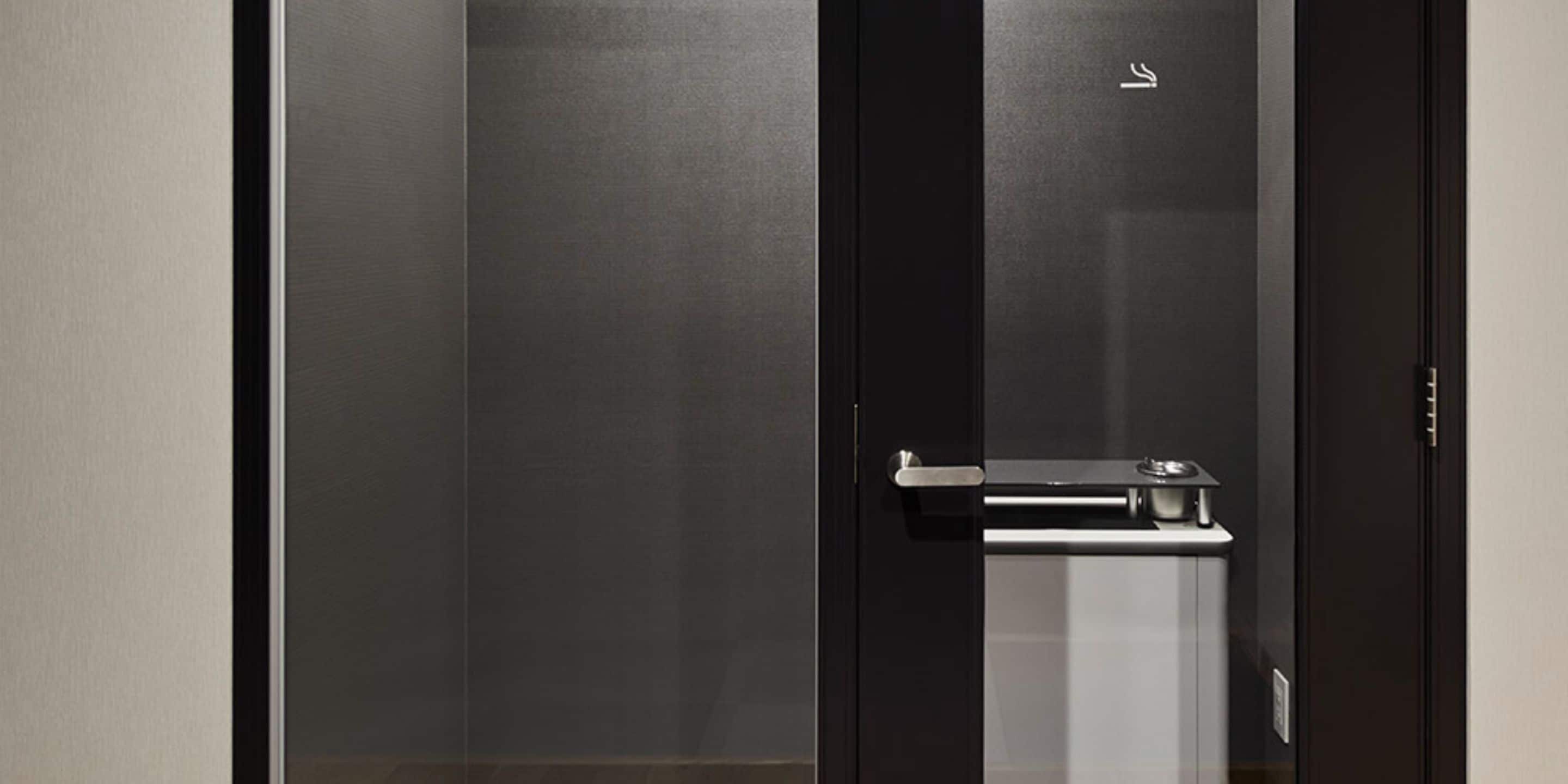 A modern elevator with a metallic handrail and a small control panel.