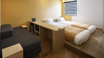 Une chambre d’hôtel de taille réduite, comprenant un lit, un bureau, une chaise et un canapé.