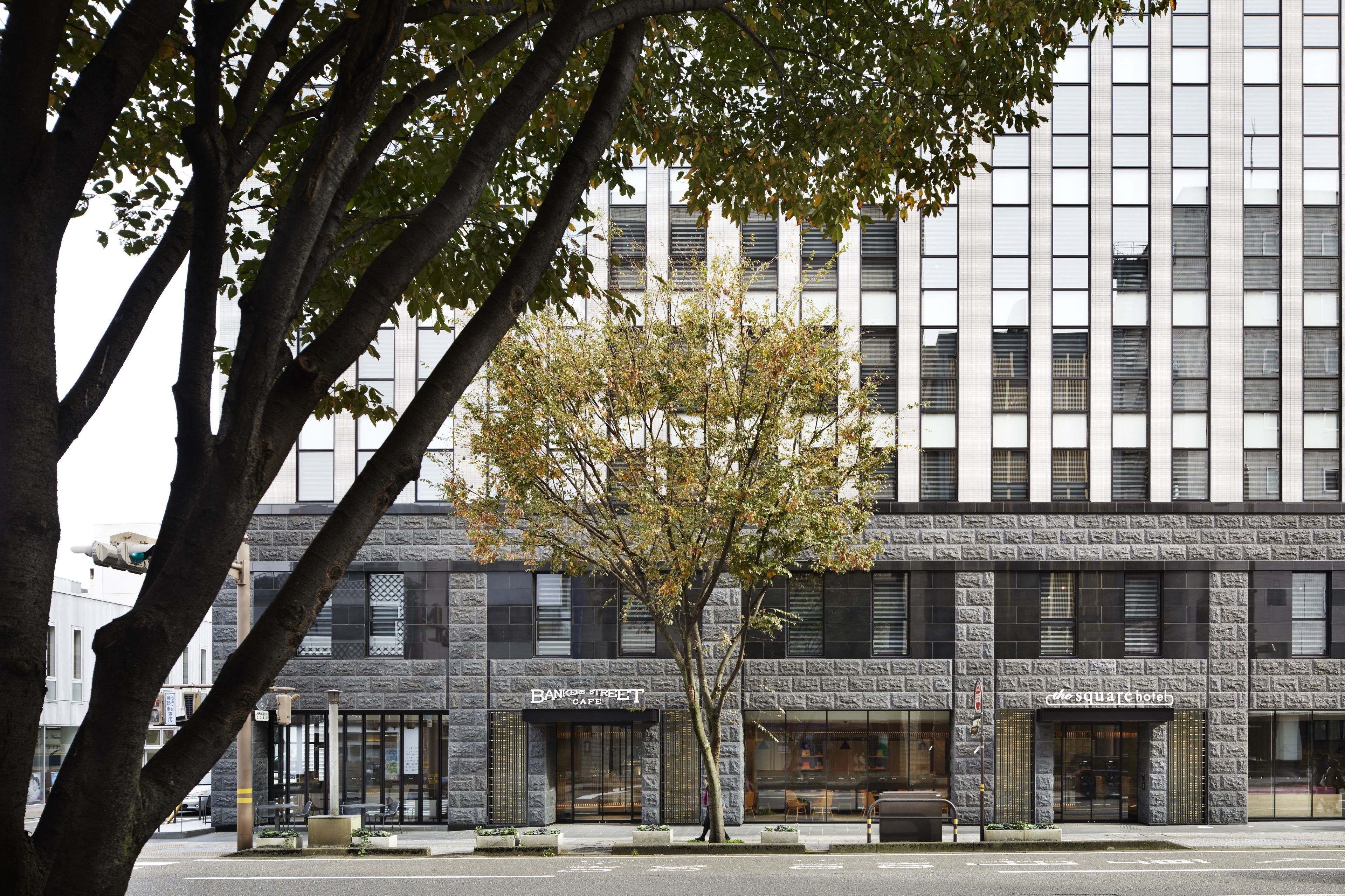 A modern building with a stone facade, featuring a cafe and a hotel.