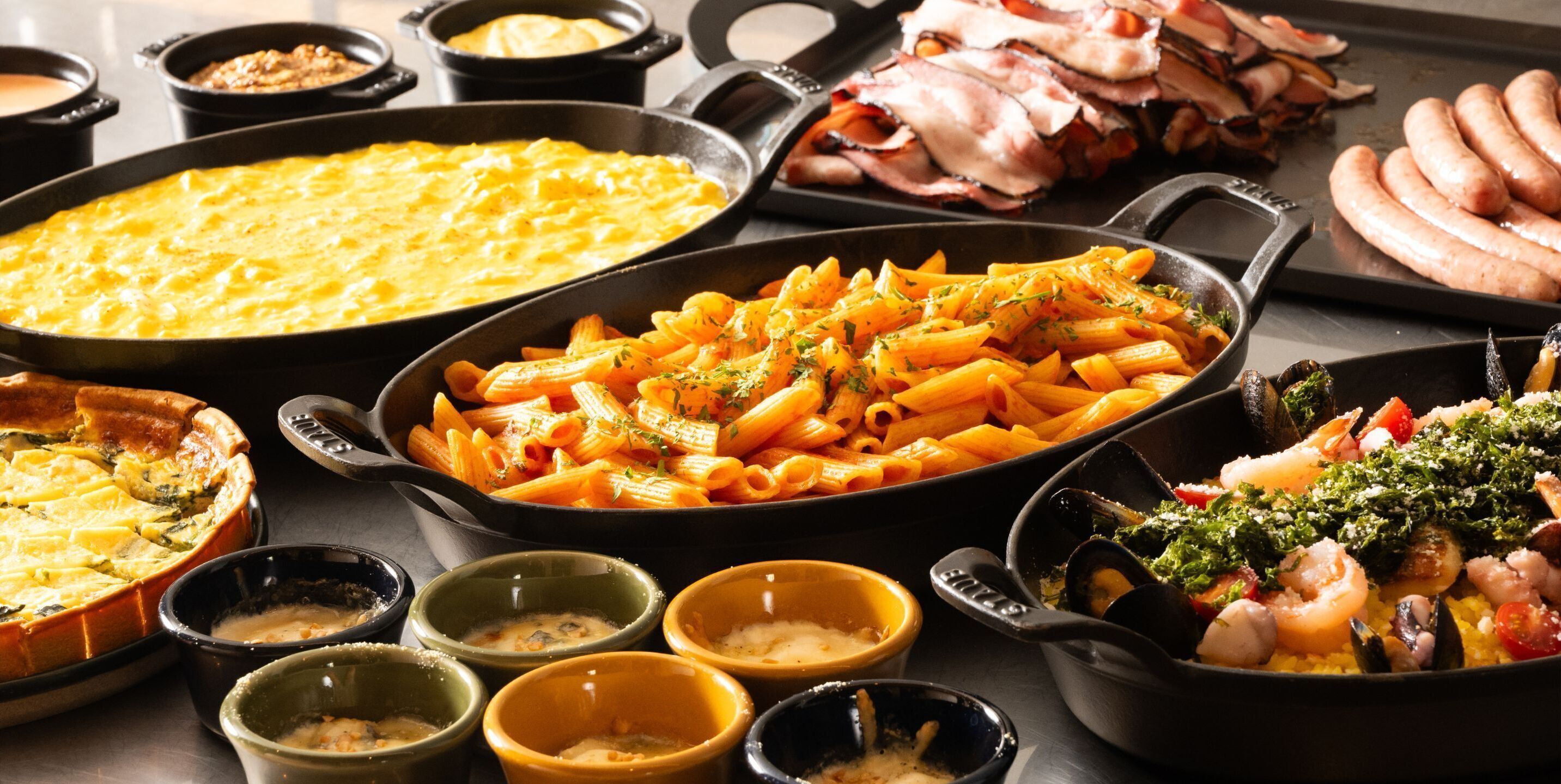 A variety of dishes including pasta, seafood, and quiche on a table.