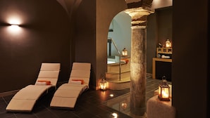 A spa area with two reclining chairs, a stone column, and two lit lanterns. - The Code Hotel (Rome)