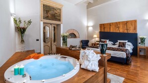 A modern hotel room with a large bathtub, a bed with a dark headboard, and a wooden floor. - The Code Hotel (Rome)