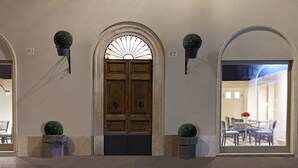 A hotel entrance with a wooden double door, two potted plants, and a glass door leading to a dining area. - The Code Hotel (Rome)