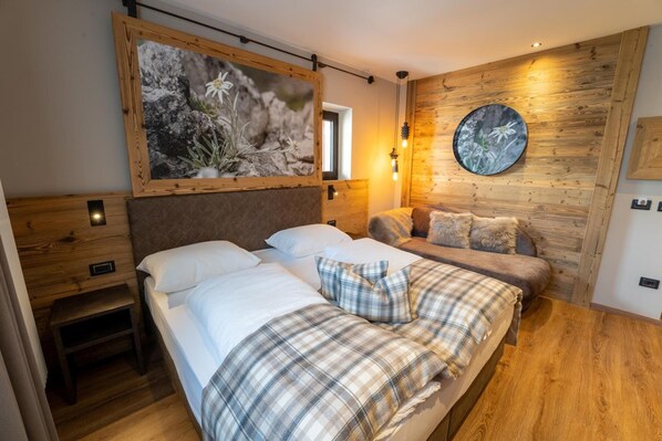 A bedroom with two beds, wooden headboards, a large framed picture, and a round mirror on the wall.