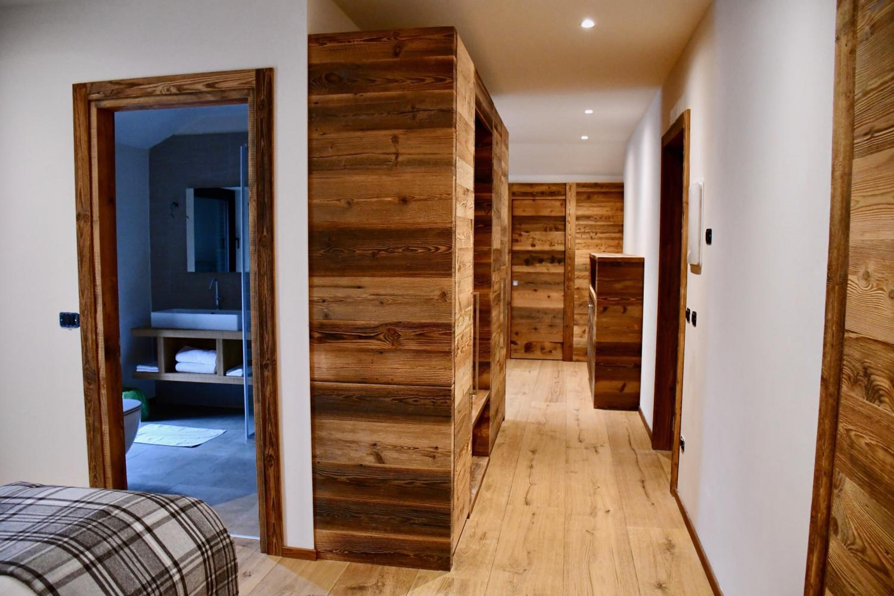A hallway with wooden paneling and a bed with a plaid bedspread.