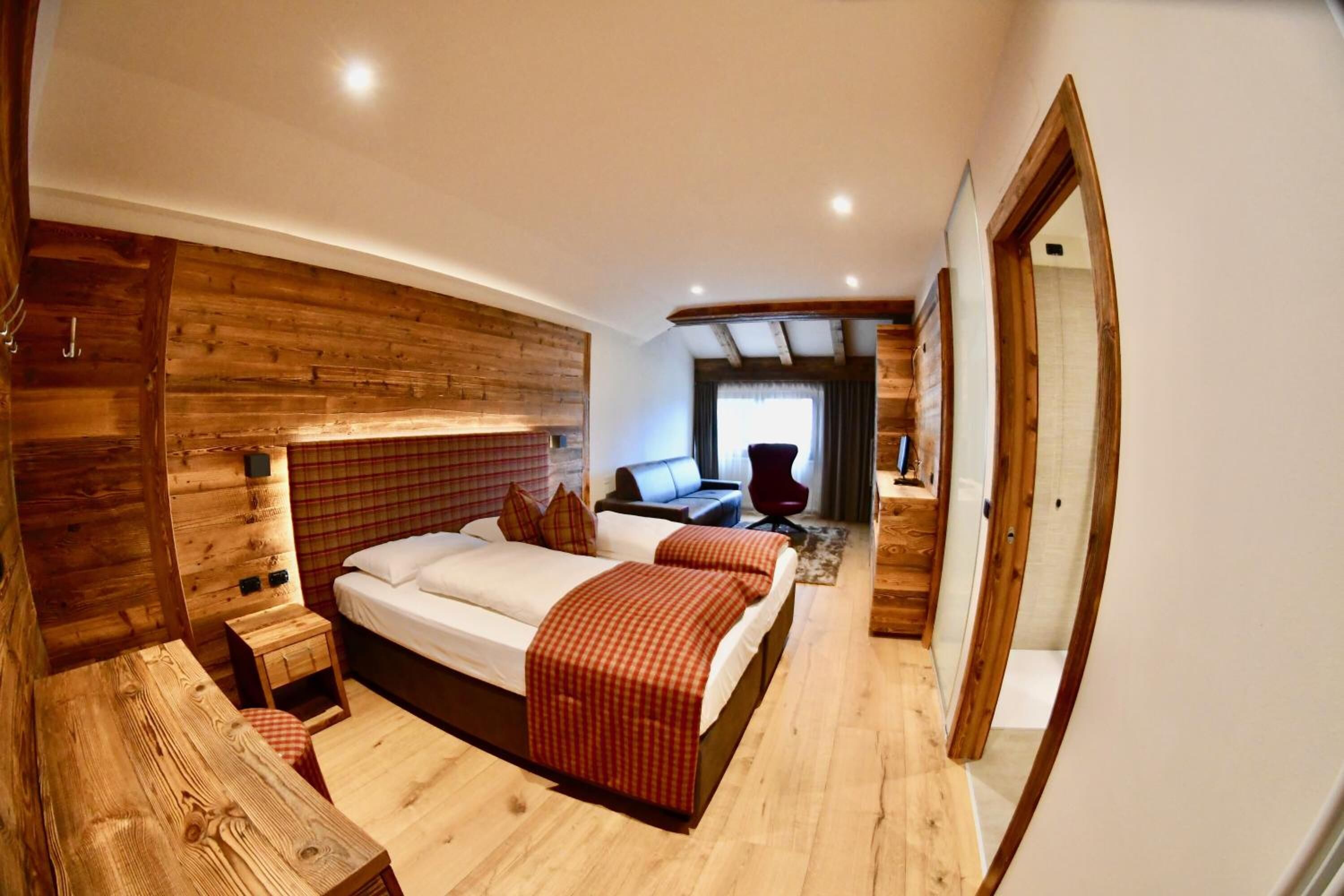 A wooden-themed bedroom with a bed, bedside tables, and a seating area.