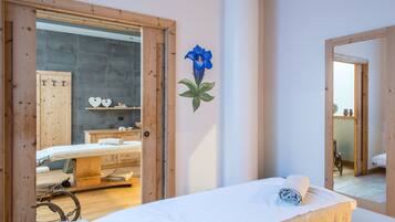 Quarto com cama de madeira, uma mesinha com toalha, espelho e parede com decoração de flores azuis.